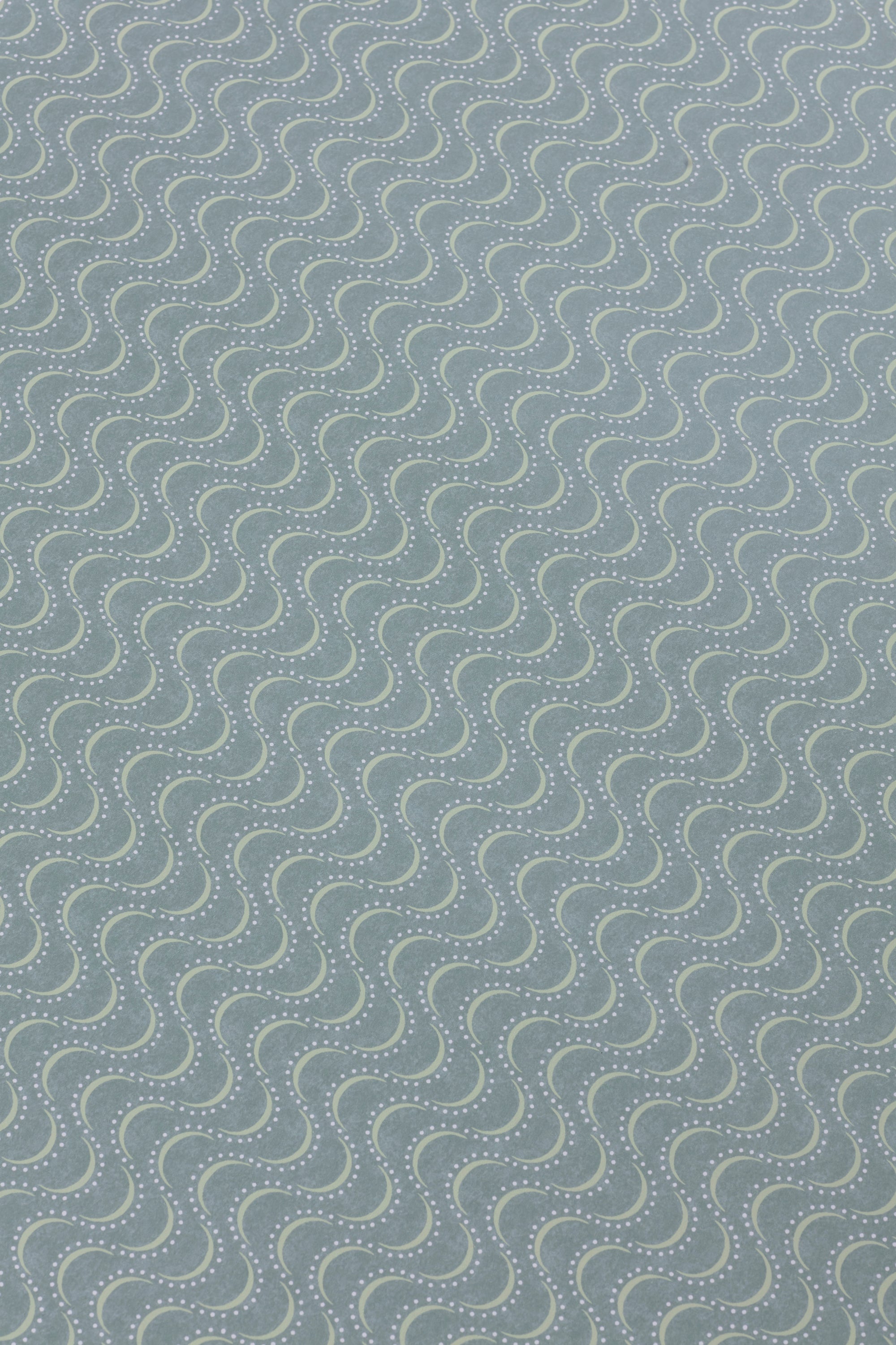 Detail of a wallpaper panel in an undulating stripe pattern in light green and blue on a turquoise field.