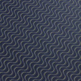 Detail of a wallpaper panel in an undulating stripe pattern in white and mustard on a dark navy field.