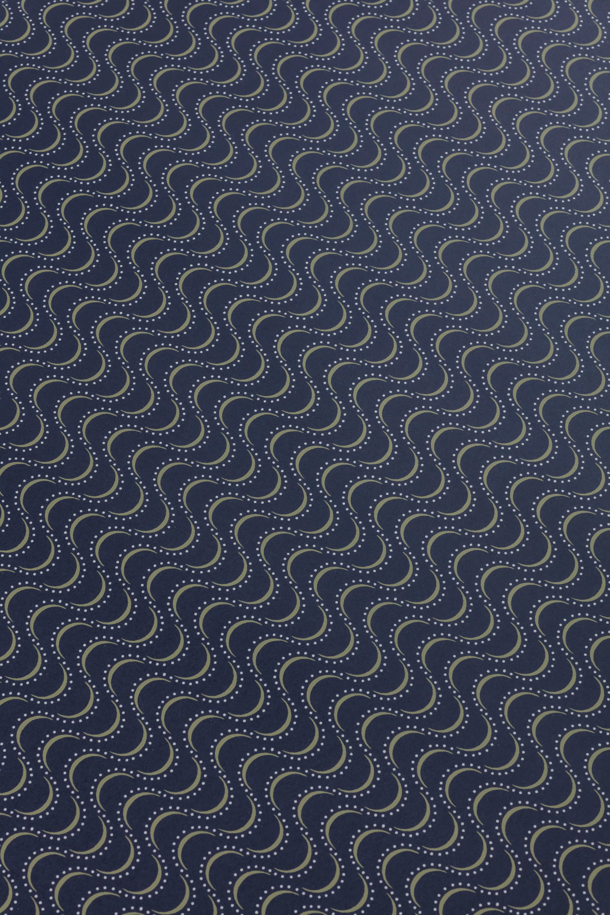 Detail of a wallpaper panel in an undulating stripe pattern in white and mustard on a dark navy field.