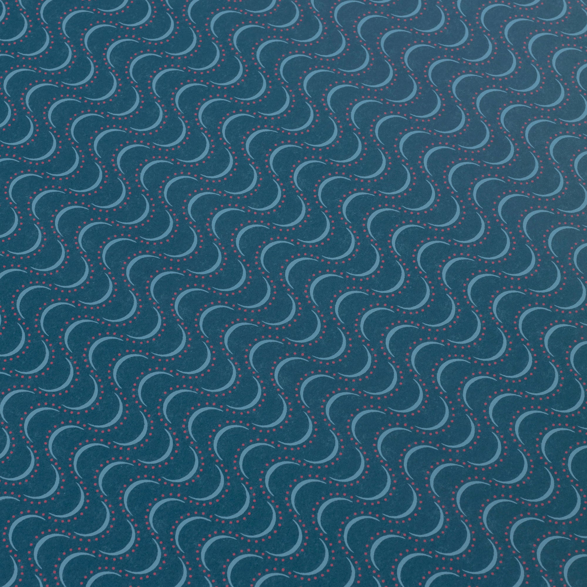 Detail of a wallpaper panel in an undulating stripe pattern in blue and pink on a navy field.