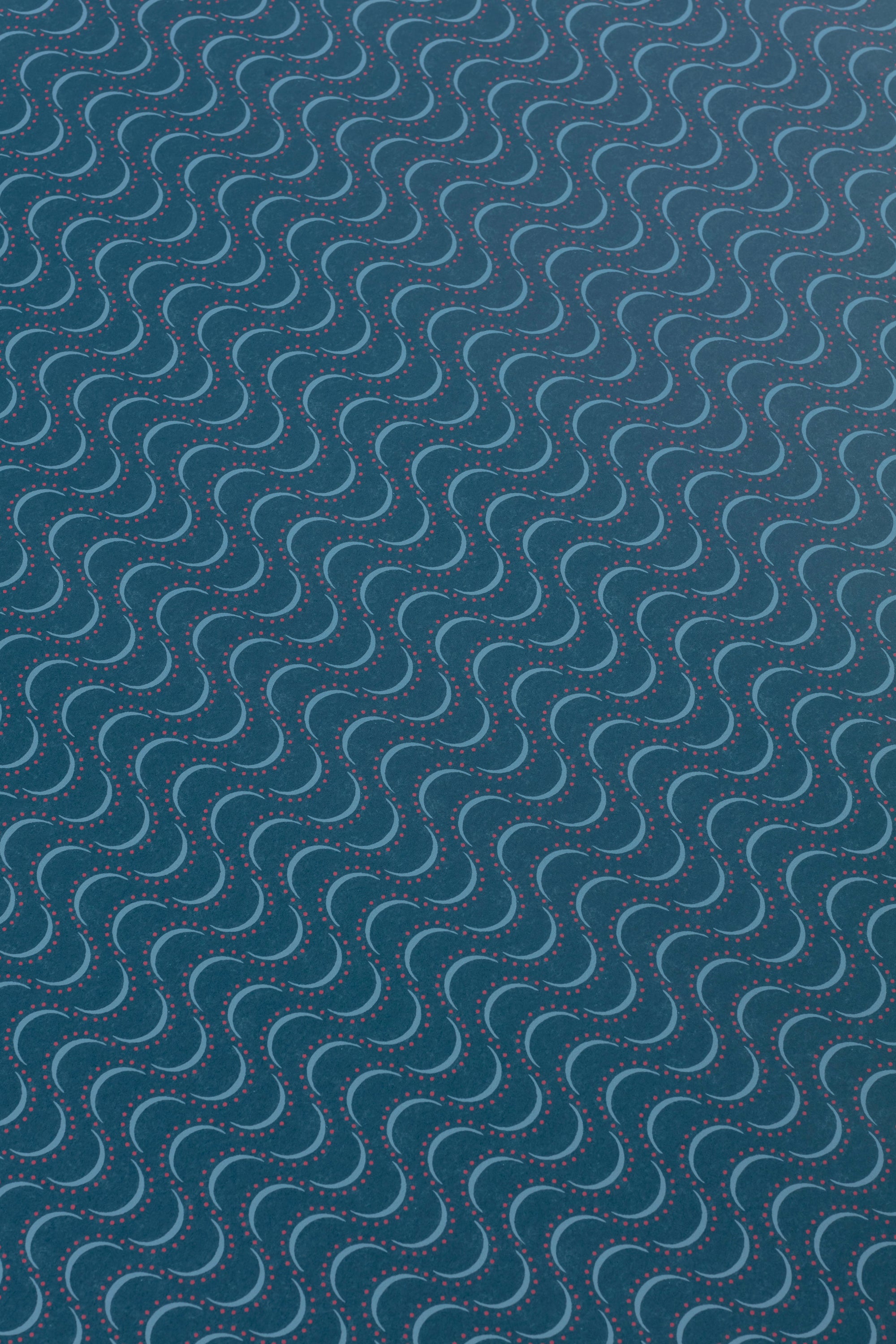 Detail of a wallpaper panel in an undulating stripe pattern in blue and pink on a navy field.
