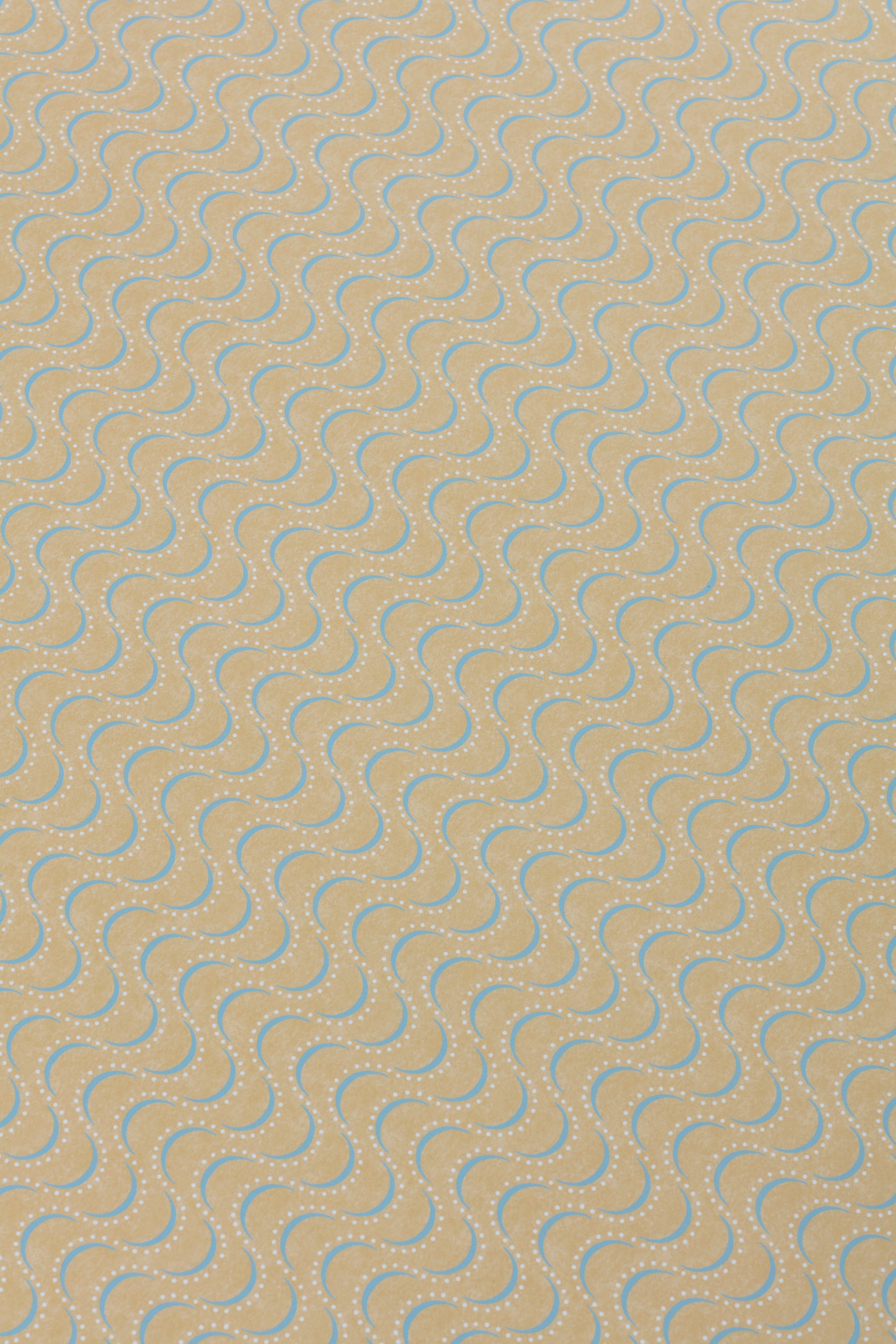 Detail of a wallpaper panel in an undulating stripe pattern in blue and white on a mustard field.