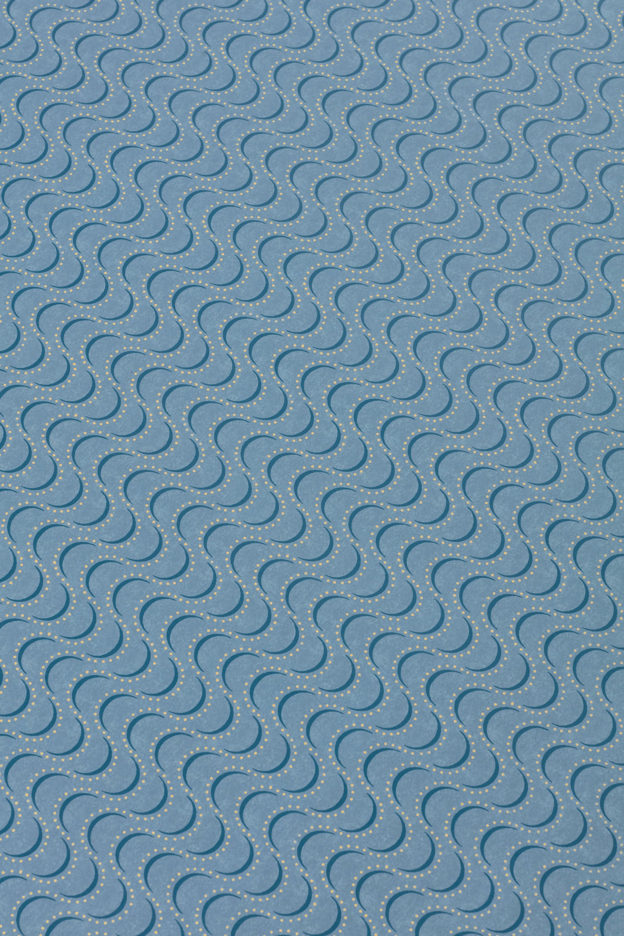 Detail of a wallpaper panel in an undulating stripe pattern in yellow and navy on a blue field.