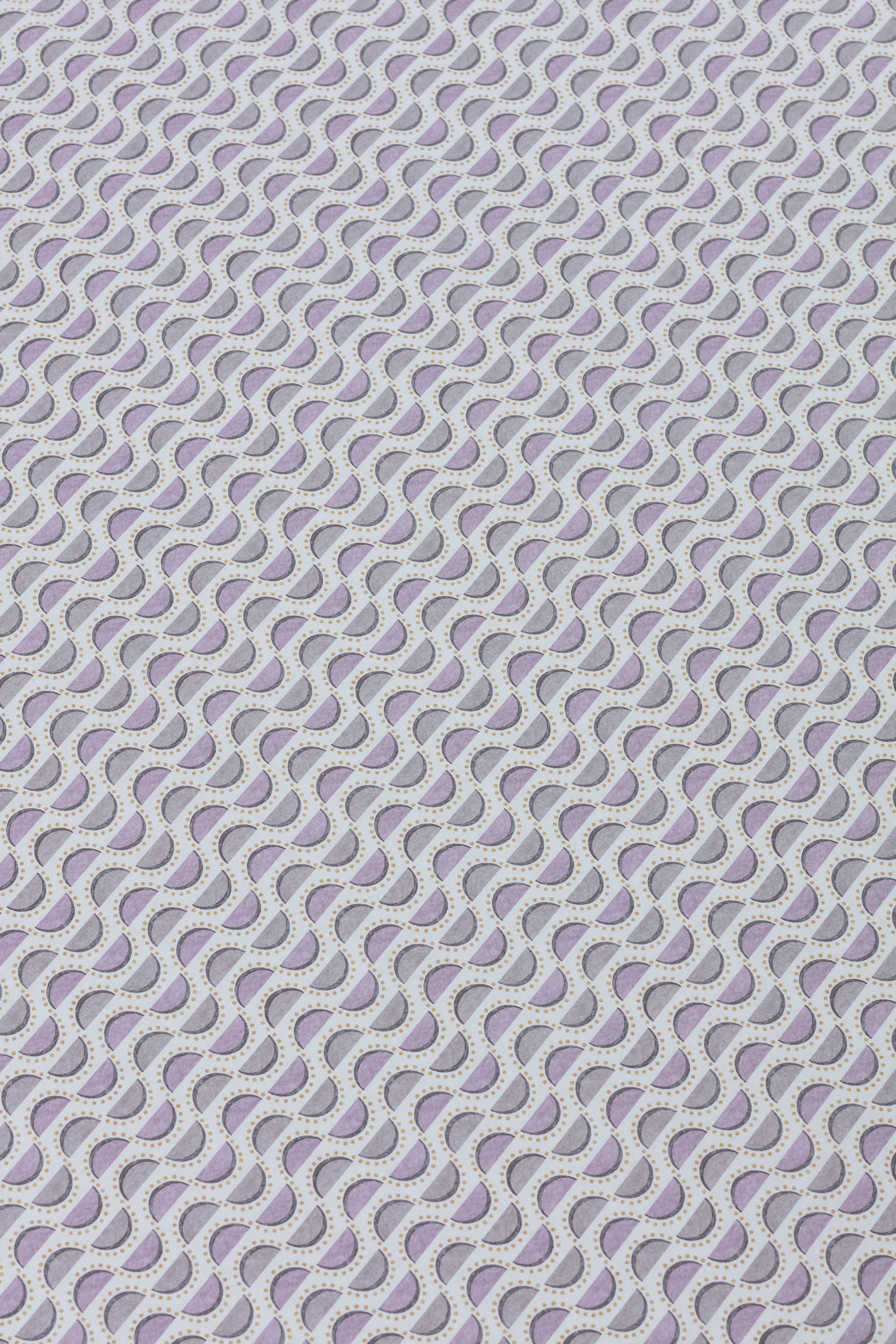Detail of a wallpaper panel in a linear geometric print in shades of purple and navy on a light blue field.