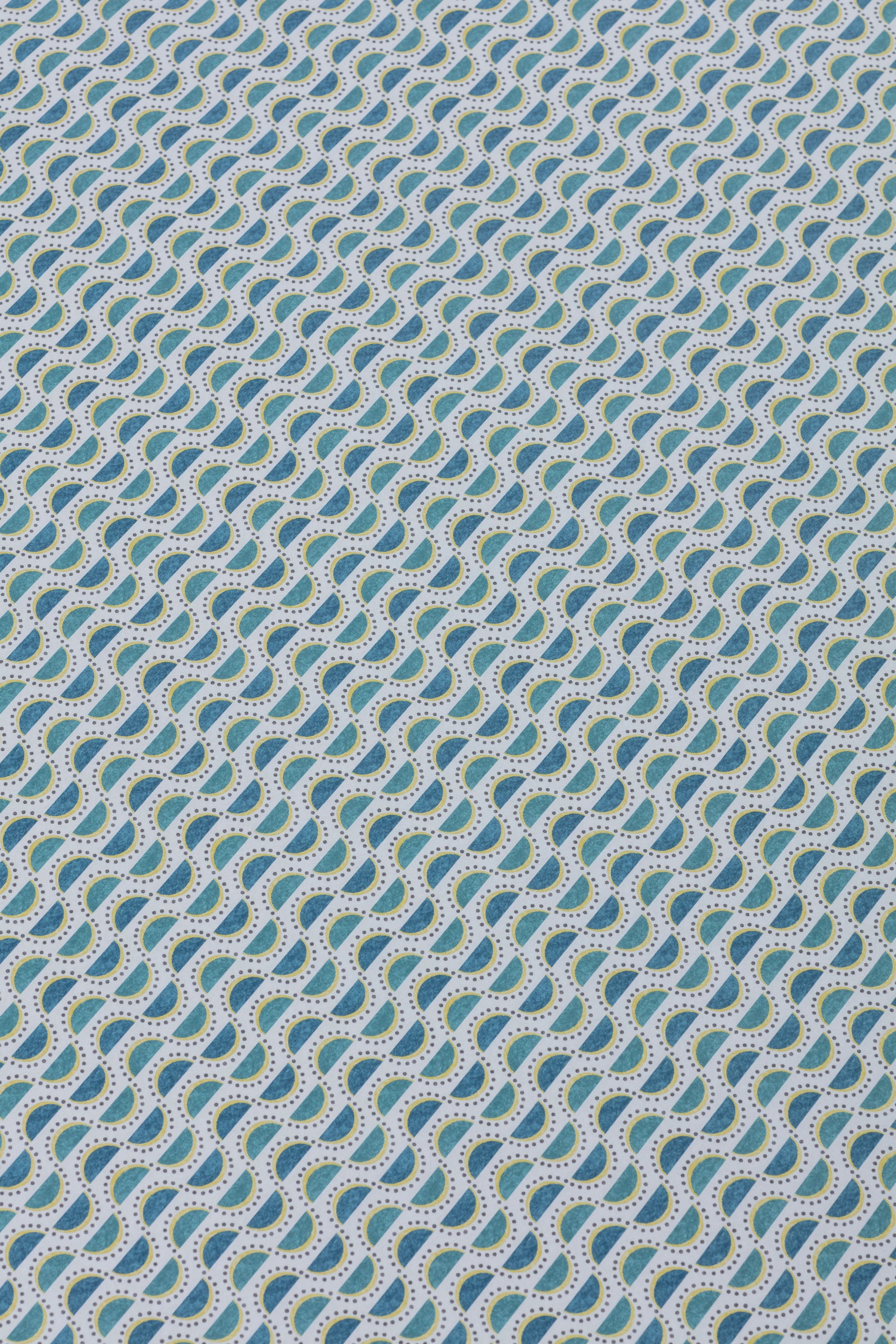 Detail of a wallpaper panel in a linear geometric print in shades of turquoise, blue and yellow on a light blue field.