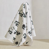 A large piece of draped fabric in an abstract geometric print in mottled green and cream on a white field.