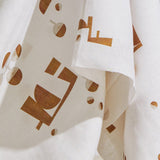 Draped fabric yardage in an abstract geometric print in mustard and cream on a white field.