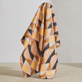 A large piece of draped fabric in a striped triangle print in shades of orange, purple, peach and cream.