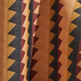 Draped wallpaper yardage in a large-scale triangle print in shades of orange, red and black.