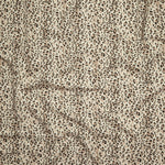 Close up of gently draped printed linen with small scale painterly animal print in black and tan on a beige background