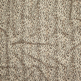 Close up of gently draped printed linen with small scale painterly animal print in black and tan on a beige background