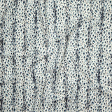 Close up of gently draped printed linen with small scale painterly animal print in navy and light blue on a white background