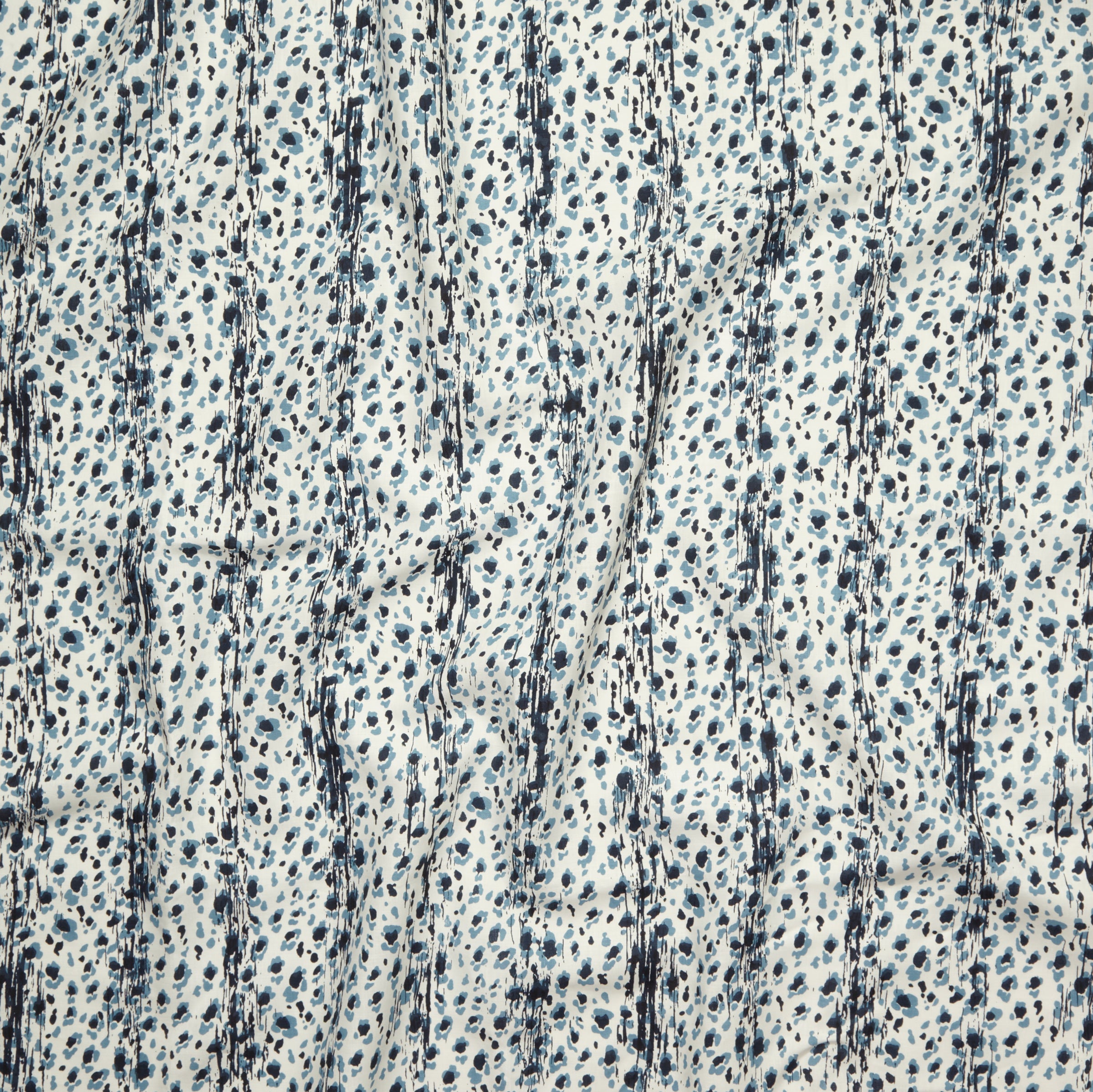 Close up of gently draped printed linen with small scale painterly animal print in navy and light blue on a white background