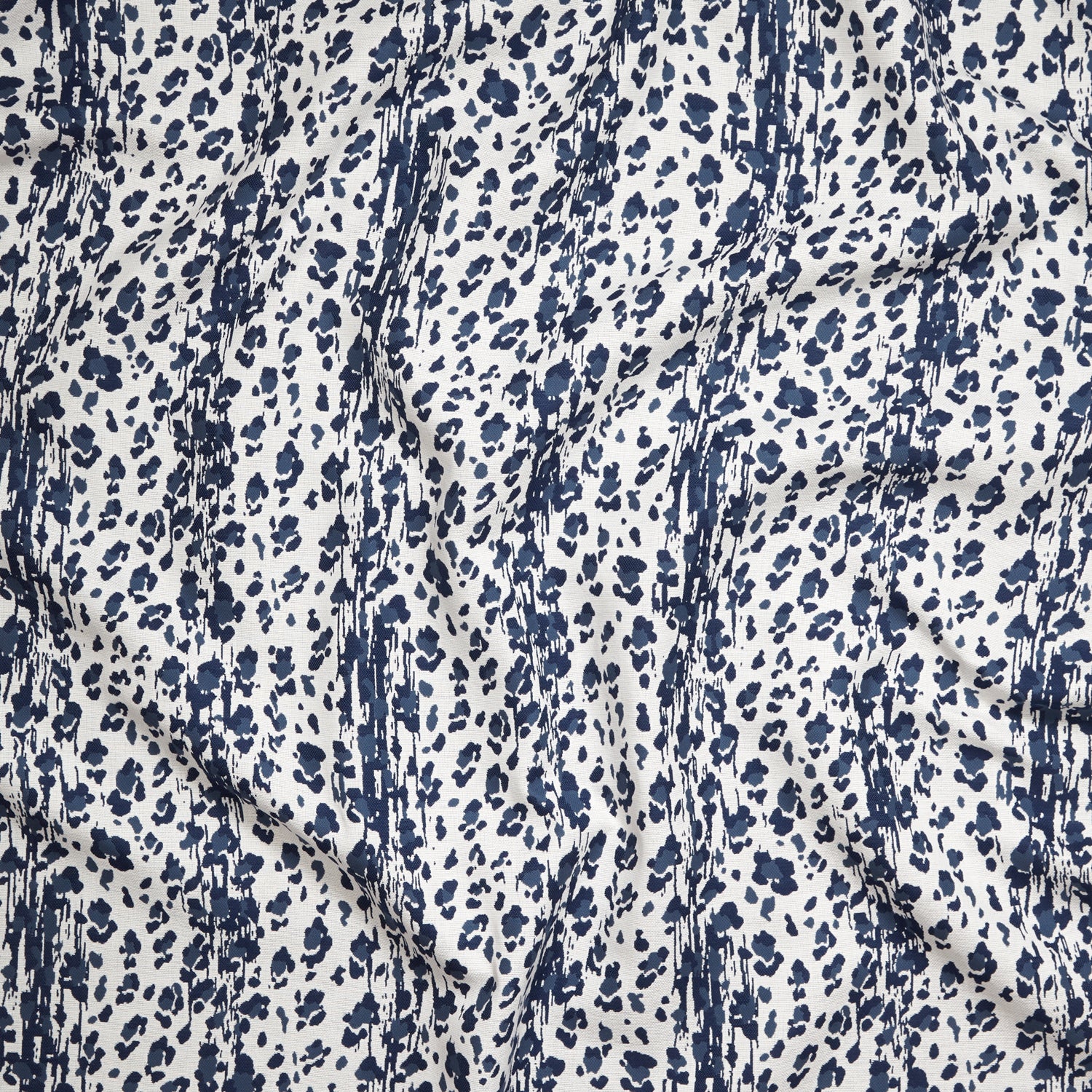 Close up of gently draped Indoor-Outdoor fabric with a painterly animal print in dark blue on white. 