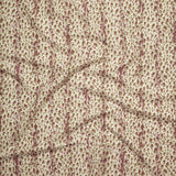 Close up of gently draped printed linen with small scale painterly animal print in mauve and olive green on a beige background