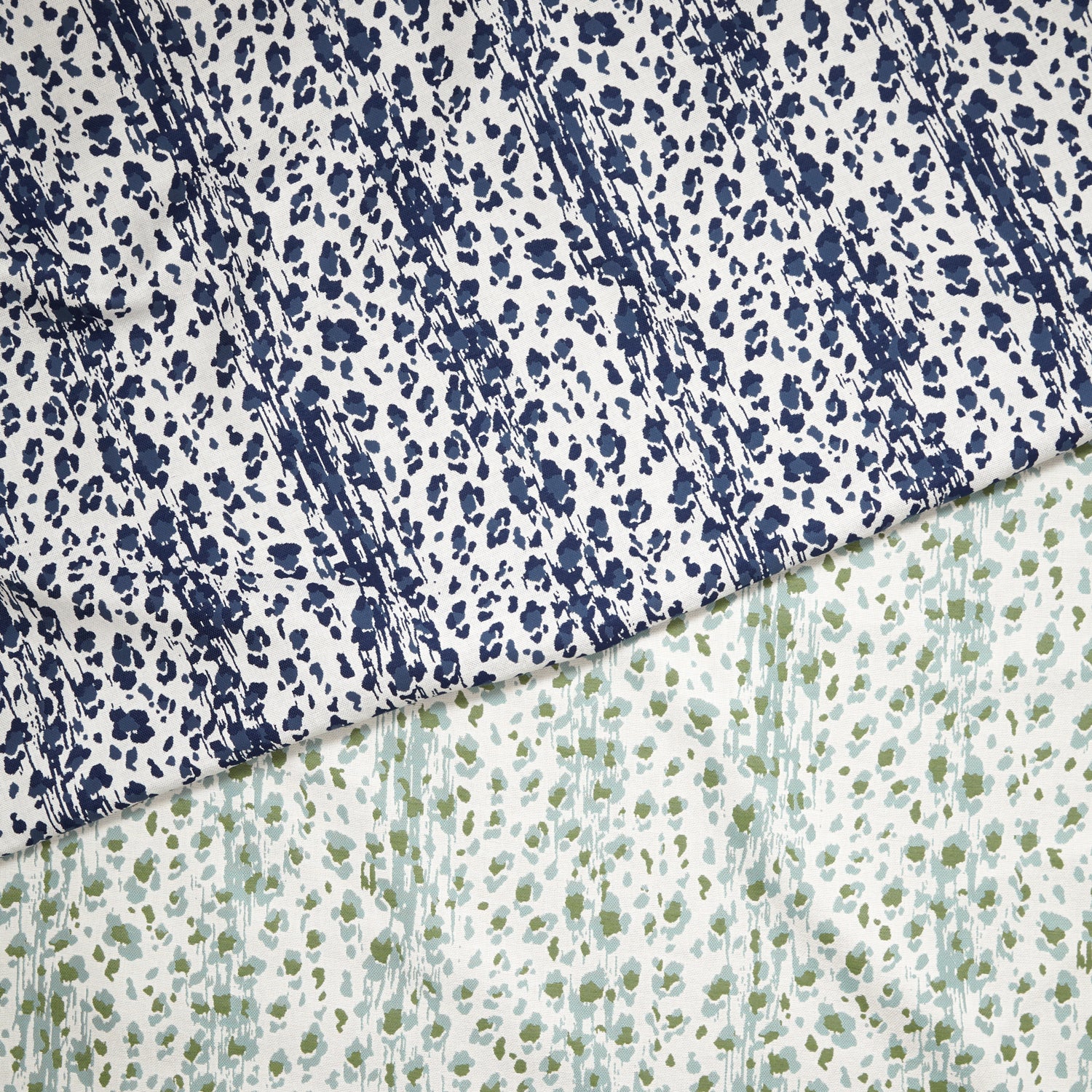 Layered fabric cuttings with a painterly animal print in navy blue and light blue and green on white. 