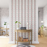 A maximalist living space with an accent wall papered in an intricate diamond stripe print in red, black and cream.
