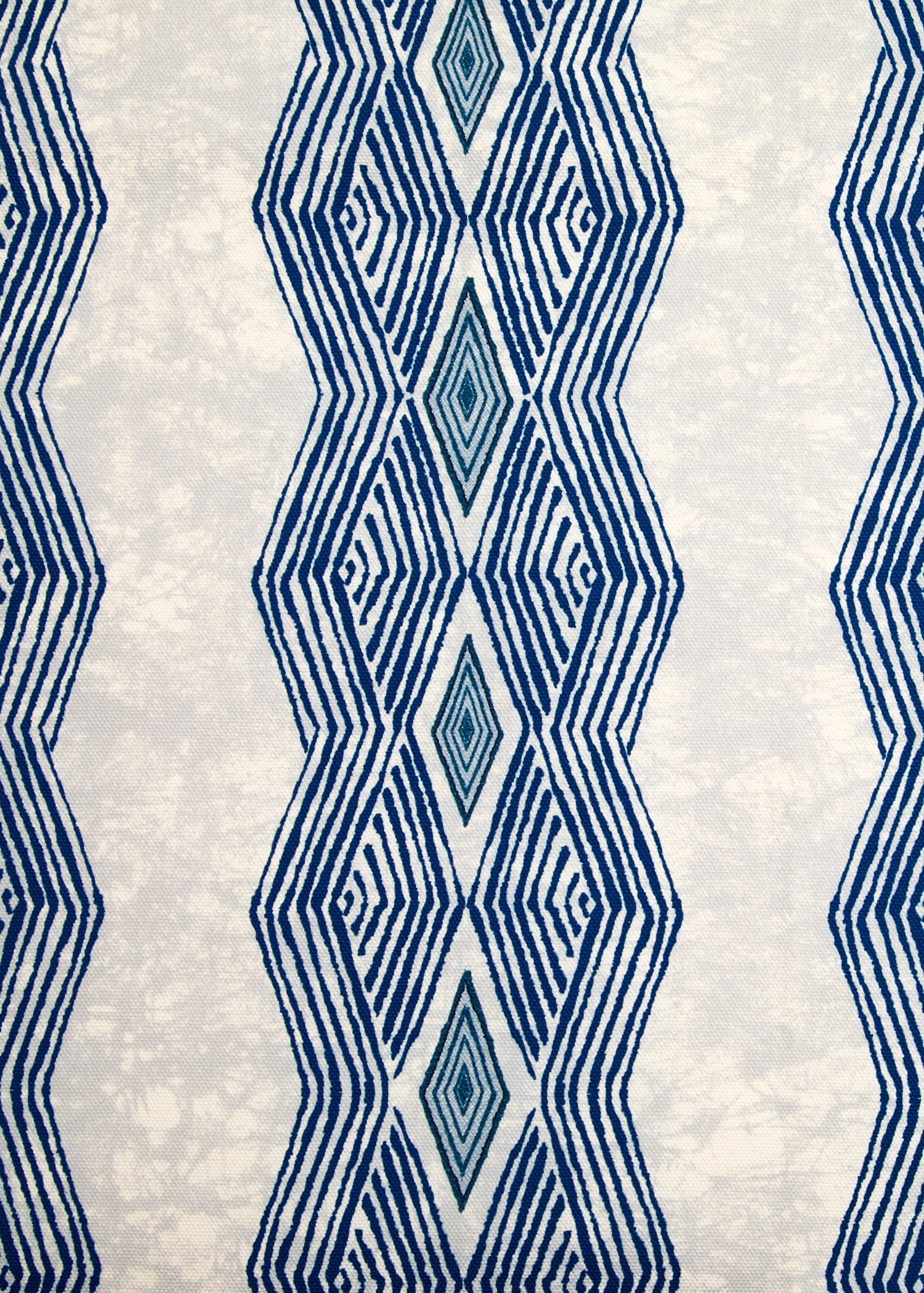 Detail of fabric in an intricate diamond stripe print in blue and navy on a cream field.