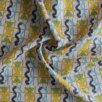 Close up of gently draped printed fabric with blue squiggles, yellow triangles,  yellow X marks on a broken grid in green on a white background. 