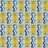 Close up of a printed wallpaper with blue squiggles, yellow striped triangles,  yellow X marks on a broken grid in green on a white background. 