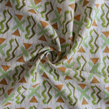 Close up of gently draped printed fabric with green squiggles, orange striped triangles, light green X marks on a broken grid in blue on a white background. 
