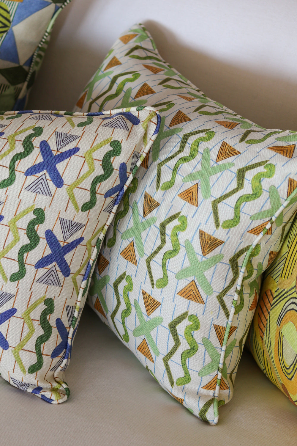 Detail of stacked throw pillows in a squiggle and x pattern in various colors. 