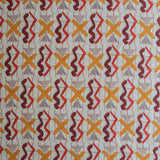 Close up of printed fabric with red squiggles, pink striped triangles, orange  X marks on a broken grid in orange on a white background. 