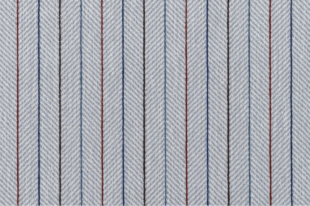 Broadloom carpet in a grey herringbone stripe with blue, red and brown pinstripes. 