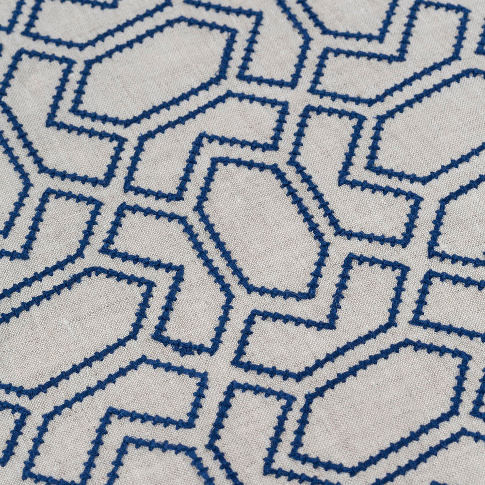 Detail of fabric with an embroidered geometric grid print in navy on a light gray field.
