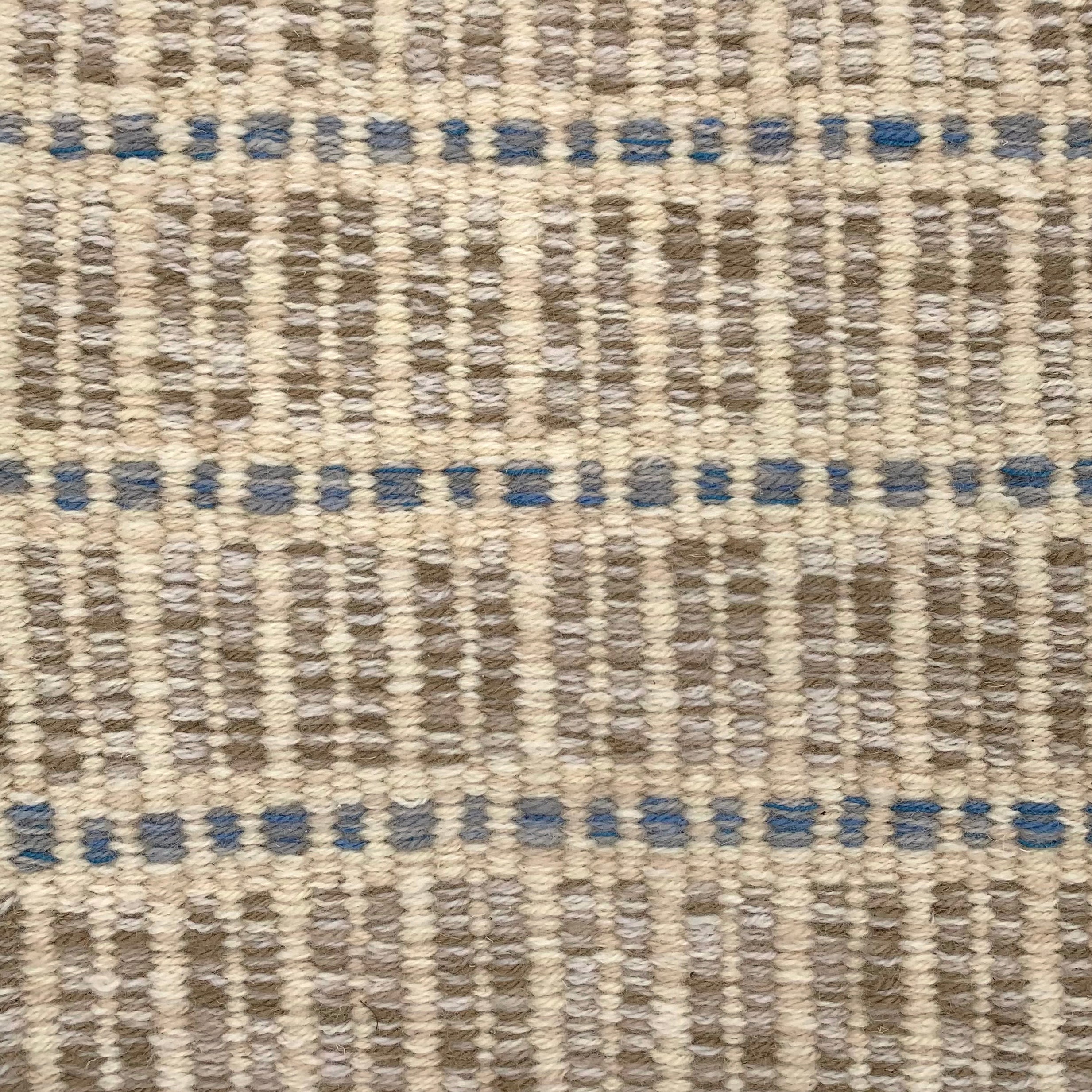 Handwoven rug detail in a textural stripe design in blue, grey and cream