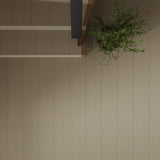 Overhead image of a staircase and landing with a potted plant  and wall to wall herringbone carpet in beige with pink accent stripes. 