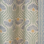 Draped printed linen in a playful dense blue and yellow with radiating green lines on a cream field. 