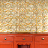 Curtain in playful yellow floral linen with an orange wooden credenza with taper candles and ceramic plate. 