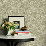 Decorative table with books and flowers against a green floral wallpapered wall.
