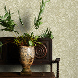 Potted plant on a wooden cabinet with decorative taupe floral wallpaper in the background