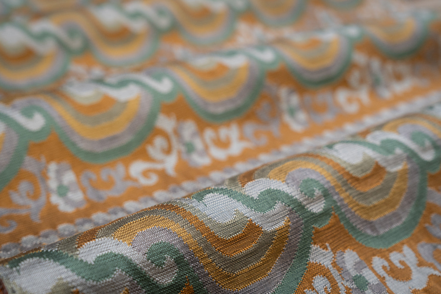 Close-up of patterned fabric with orange, green, and gray colors.