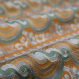 Close-up of patterned fabric with orange, green, and gray colors.