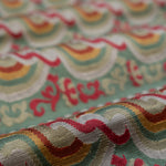 Close-up of colorful fabric with wavy red and orange pattern on a green background