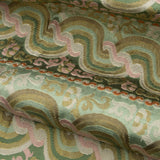 Close-up of folded handwoven silk fabric with wavy patterns in green, pink, and tan.