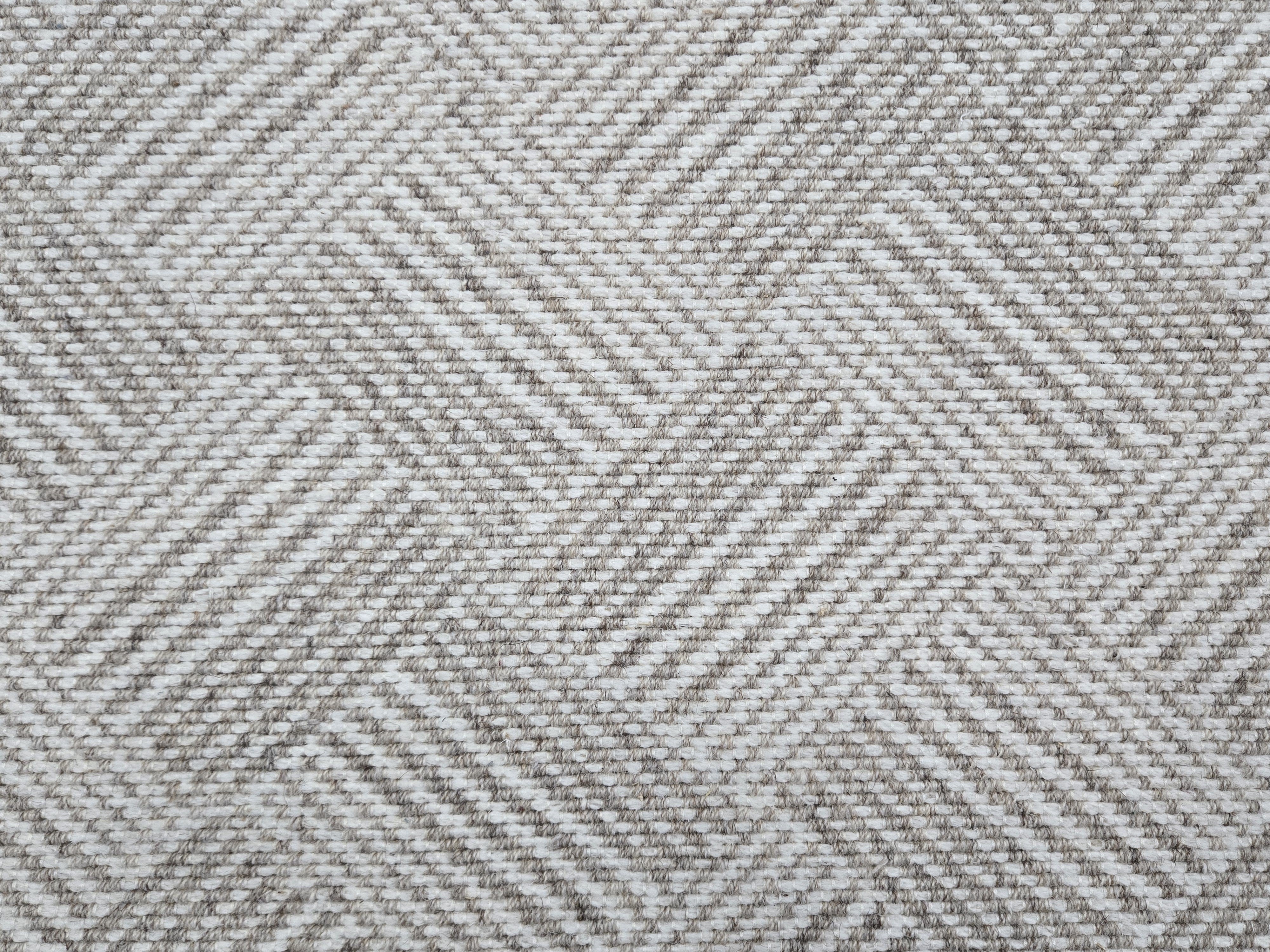 Broadloom rug sample in a diamond pattern in stripes of white and oatmeal. 