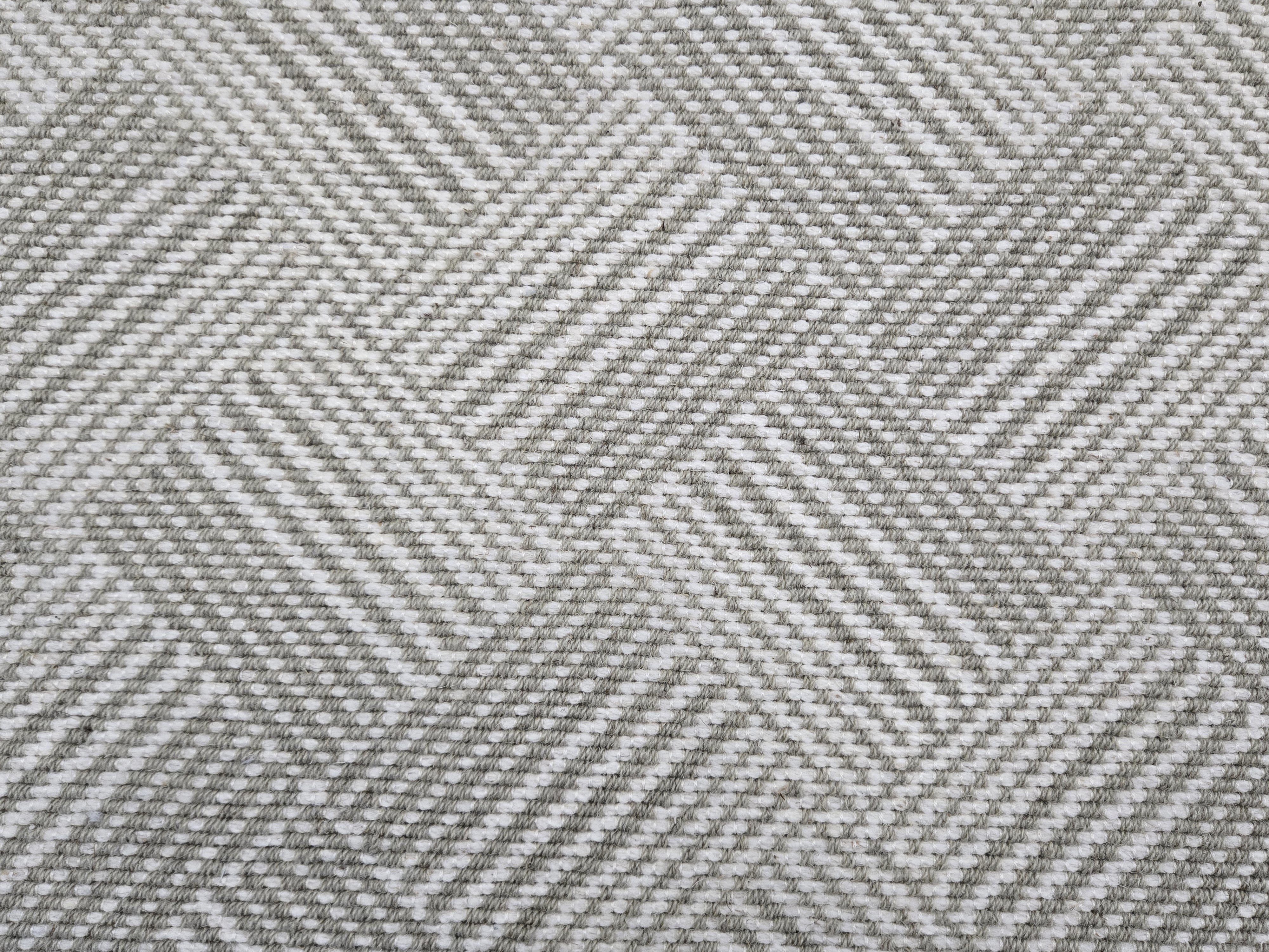 Broadloom rug sample in a diamond pattern in stripes of white and toner grey. 
