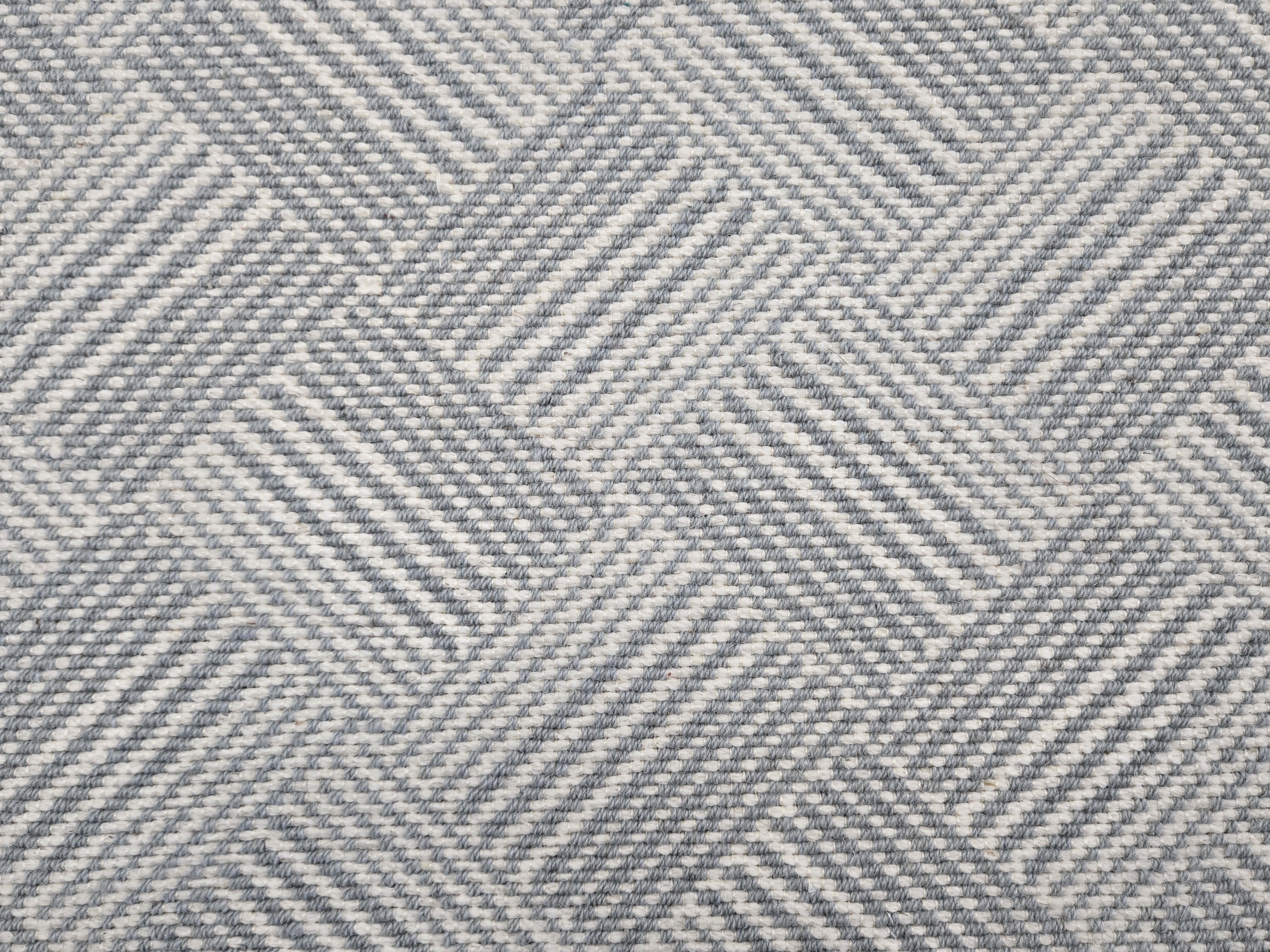 Broadloom rug sample in a diamond pattern in stripes of white and slate blue.