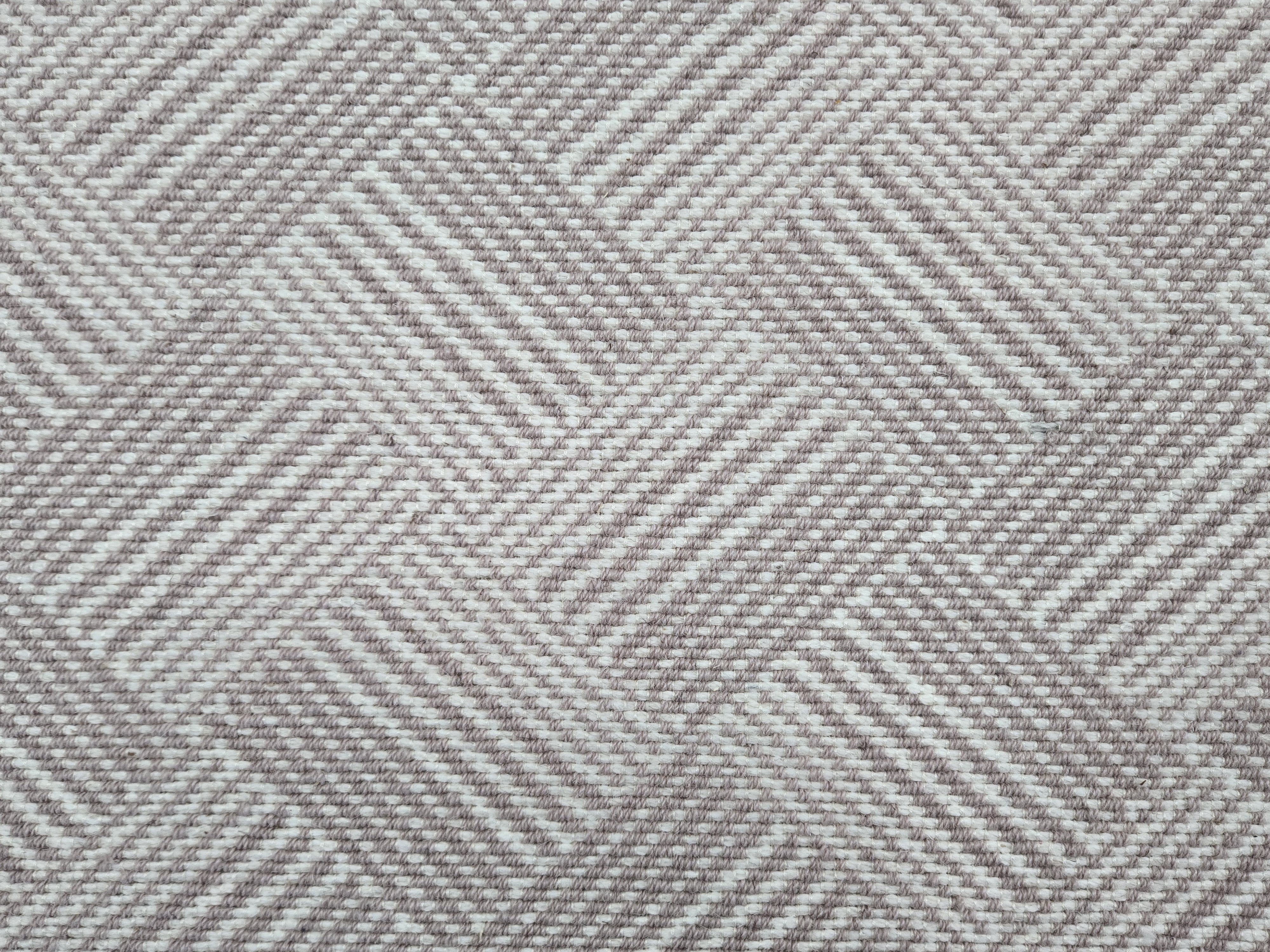 Broadloom rug sample in a diamond pattern in stripes of white and mauve.