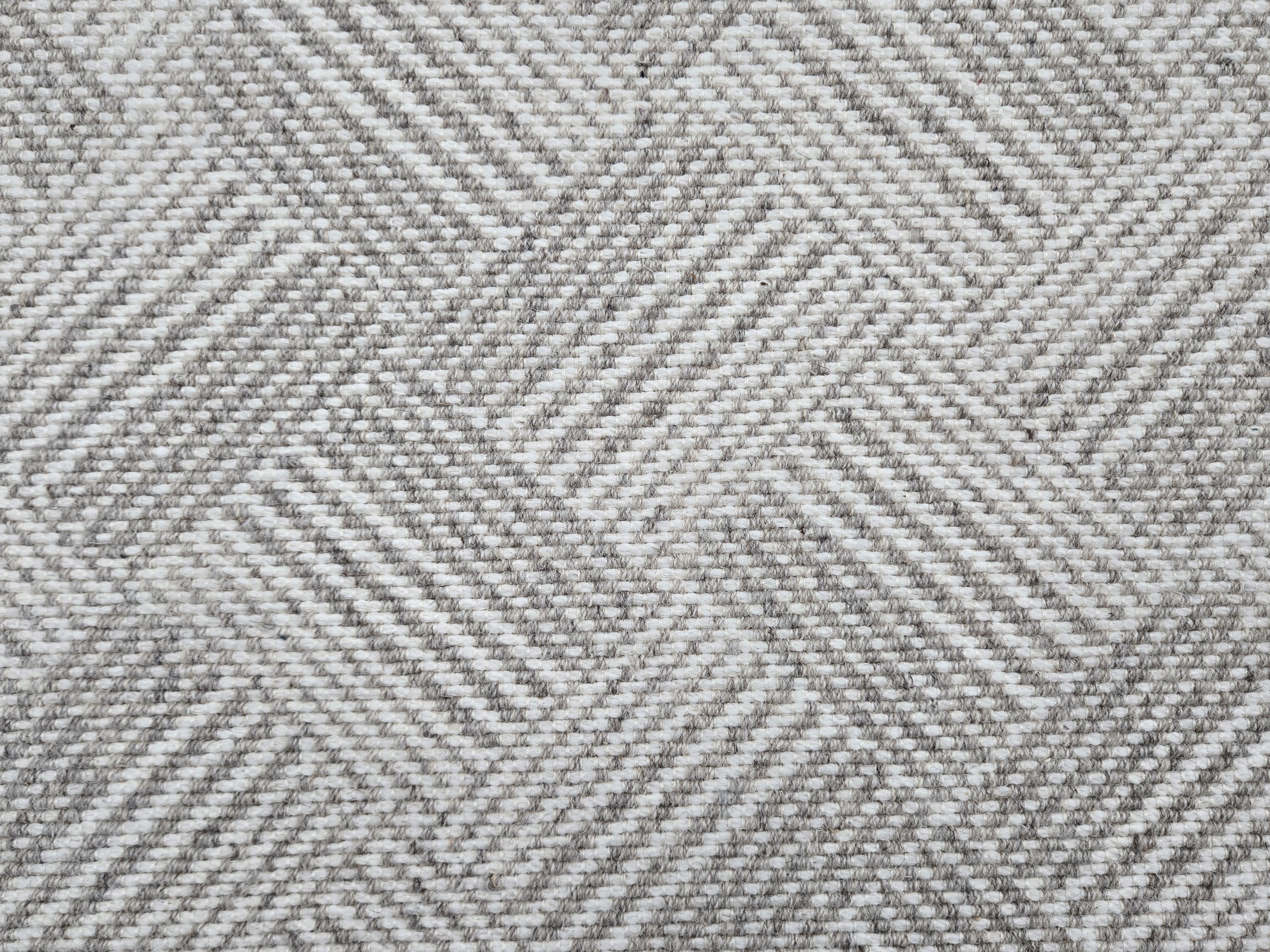Broadloom rug sample in a diamond pattern in stripes of white and heather grey.