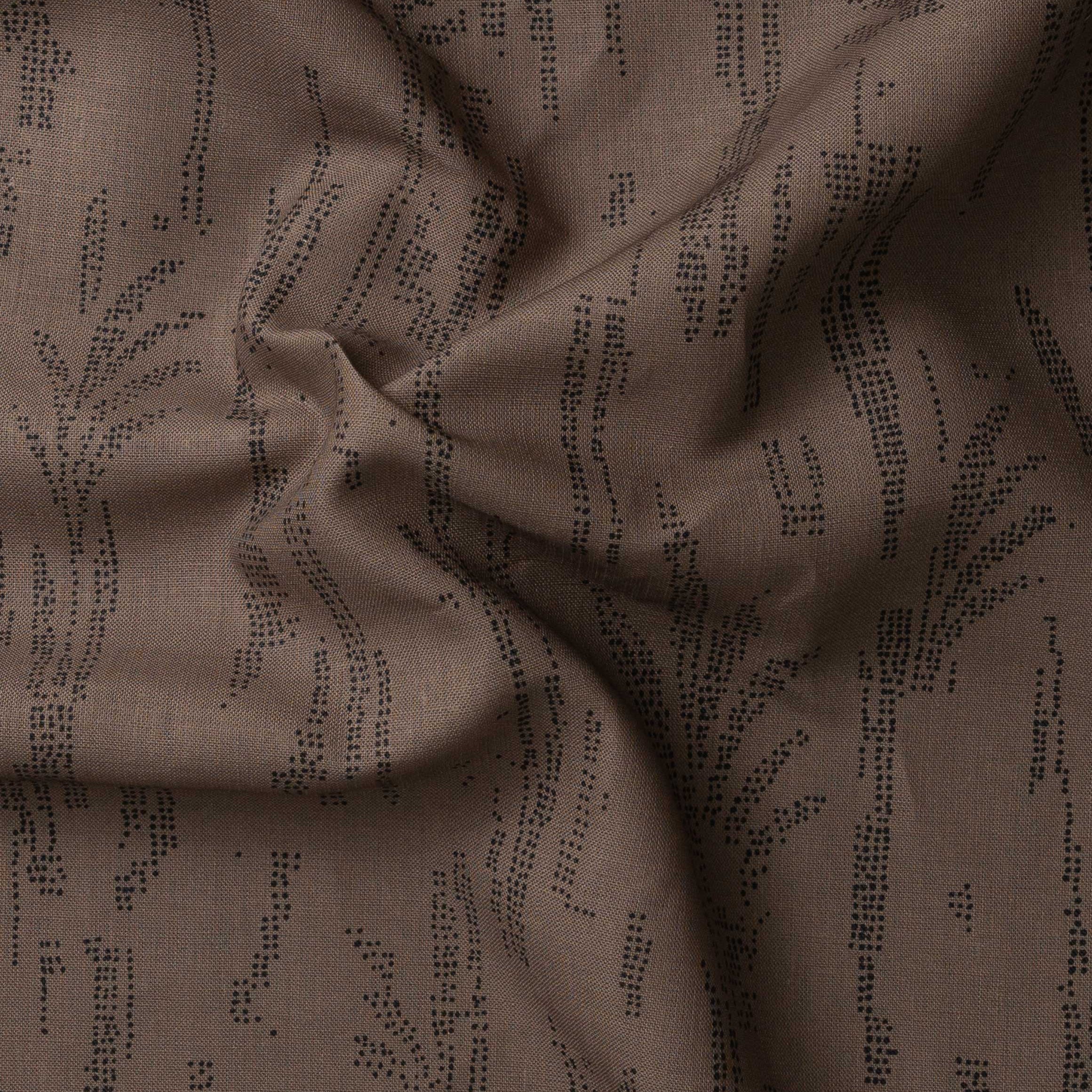 Detail of gently draped printed fabric with a black pointillist wheat frond pattern on a warm brown background. 