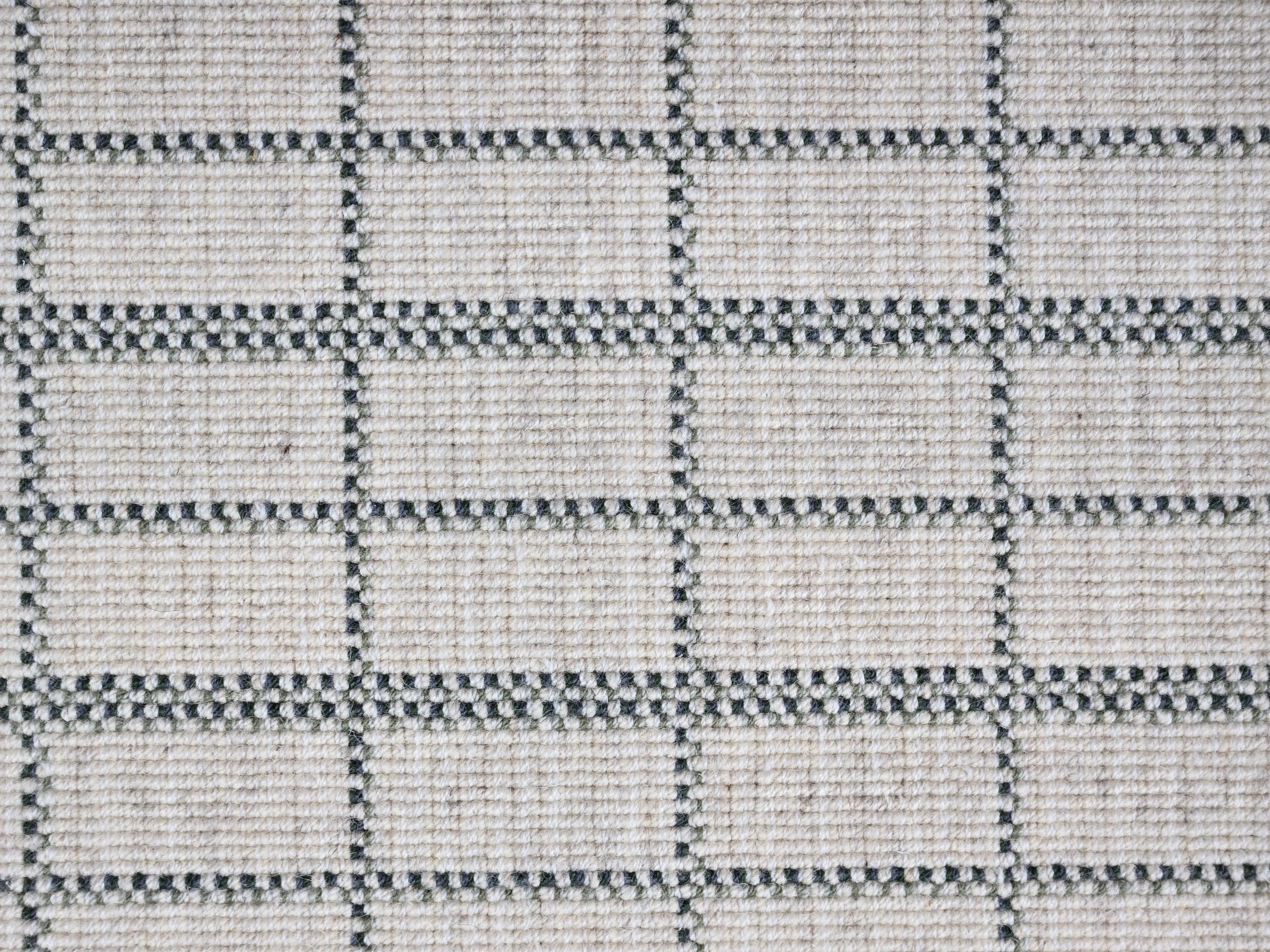 Broadloom carpet detail in plaid grid in shades of green on a beige field.