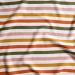Close up of gently draped striped woven Indoor-Outdoor fabric in white, olive green, pink, mustard yellow and orange.