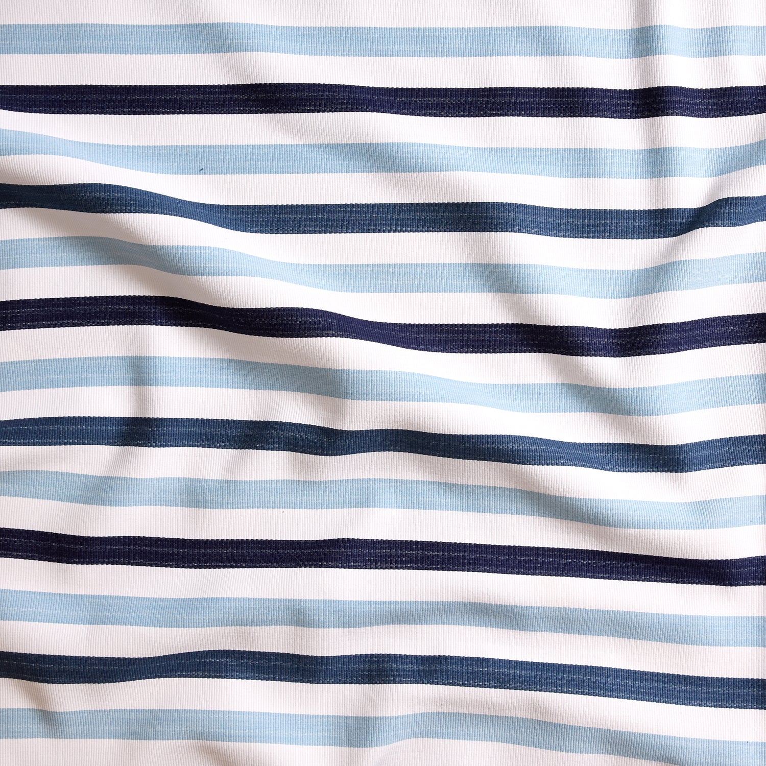 Close up of gently draped striped woven Indoor-Outdoor fabric in white, light blue navy and dark blue. 