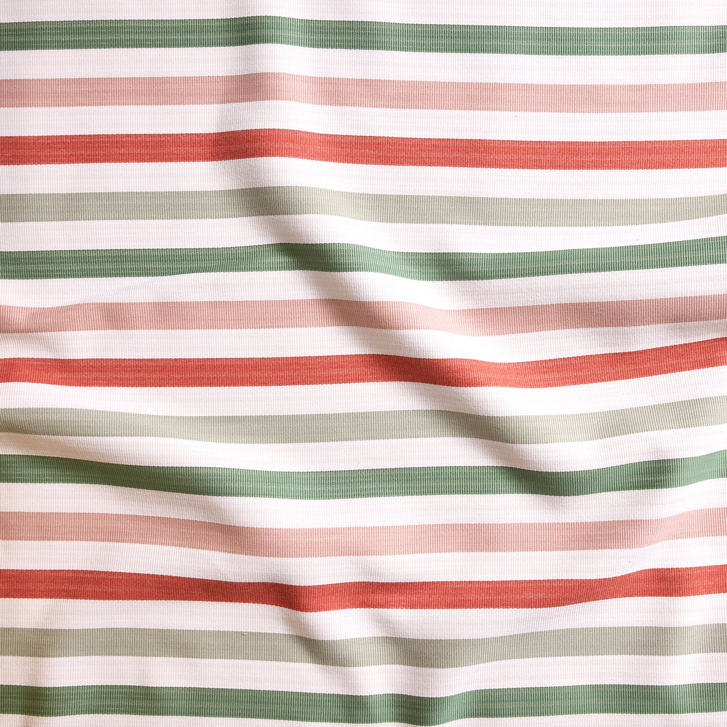 Close up of gently draped striped woven Indoor-Outdoor fabric in white, dark green, pink, coral red and sage green.