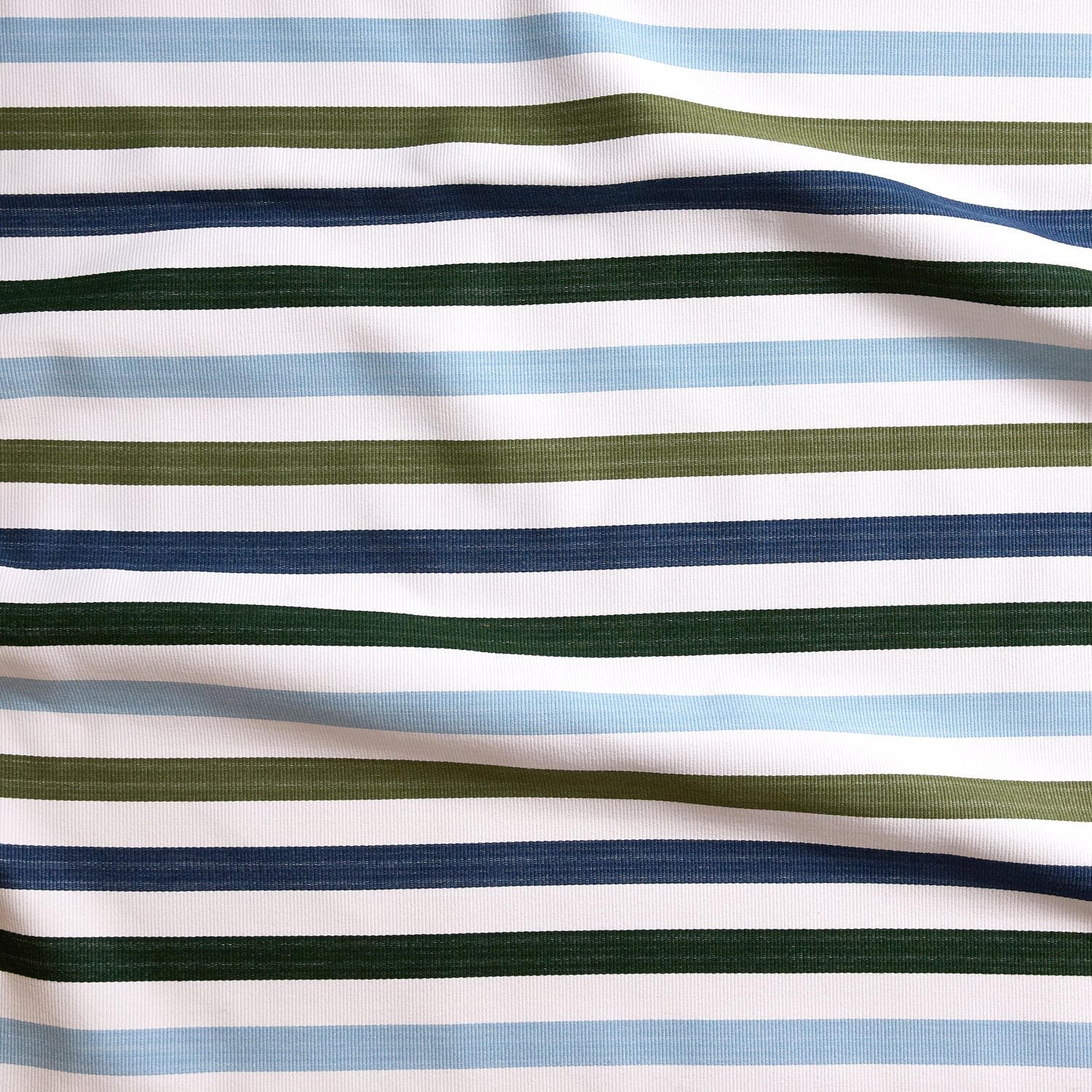 Close up of gently draped striped woven Indoor-Outdoor fabric in white, light blue, olive green, navy blue and dark green.